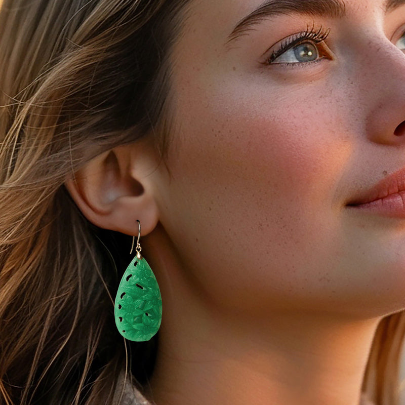 Model wearing carved green jade teardrop floral drop earrings with yellow gold earwire