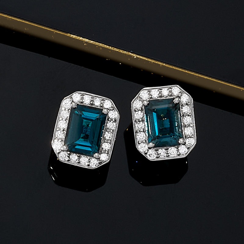 Sterling silver topaz stud earrings with blue cushion stones and diamond halo frames