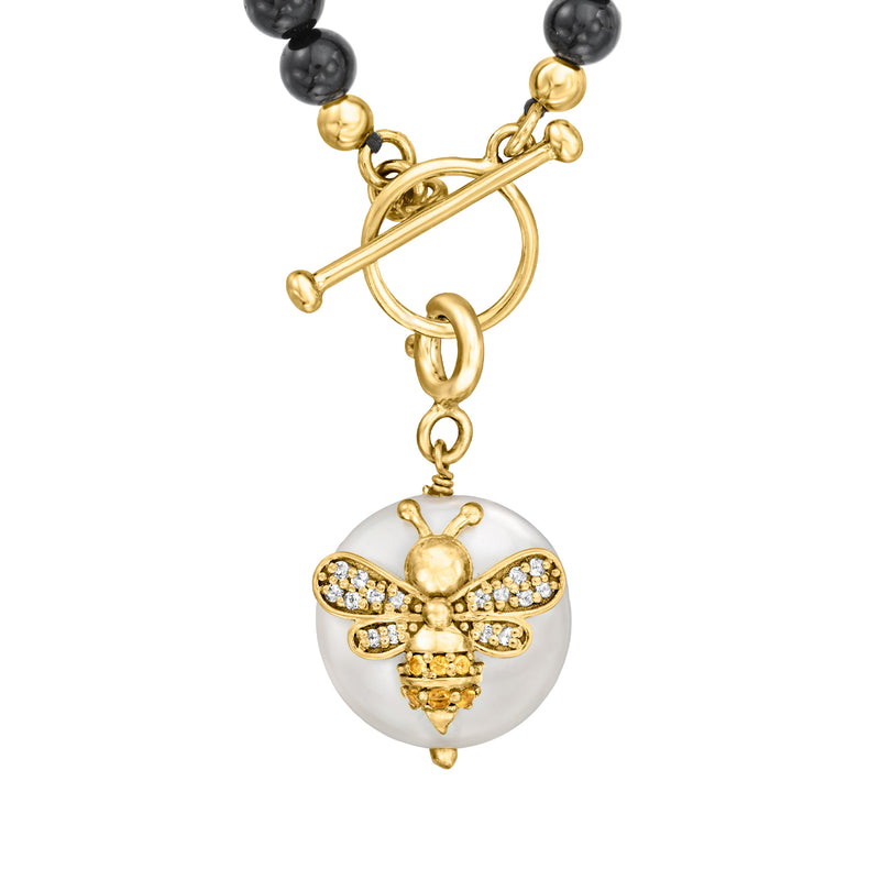 Gold-tone bee charm with round white pearl disc, crystal wings, and linked bail above