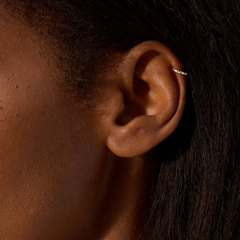 14kt yellow gold hoop earring with red ruby stones worn on ear