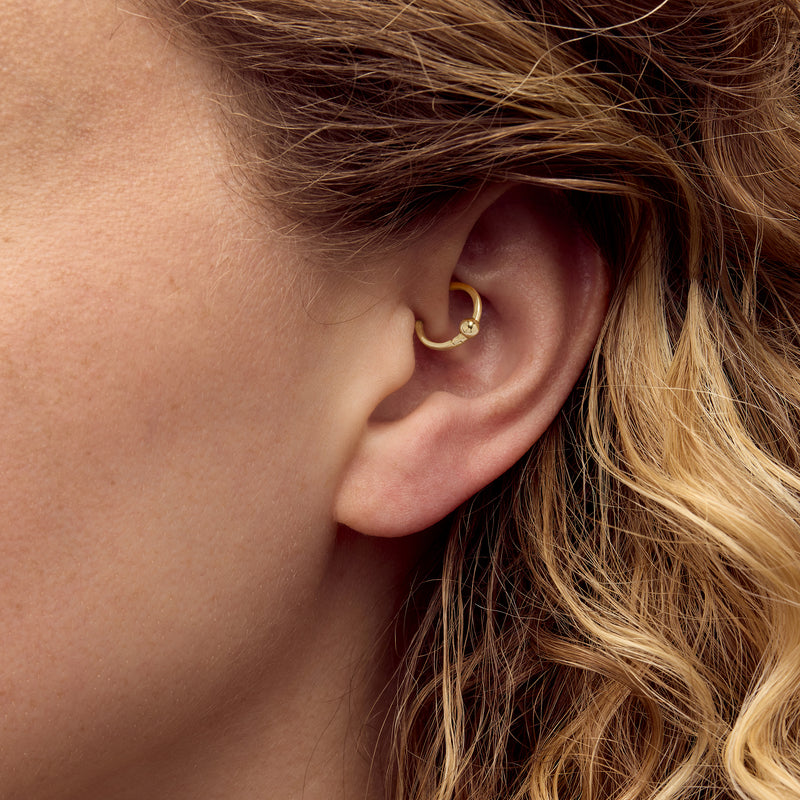 Yellow gold bead clicker hoop earring worn on ear