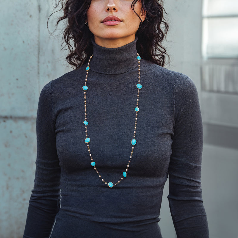 Cultured pearl necklace with turquoise blue oval drops worn on a dark top