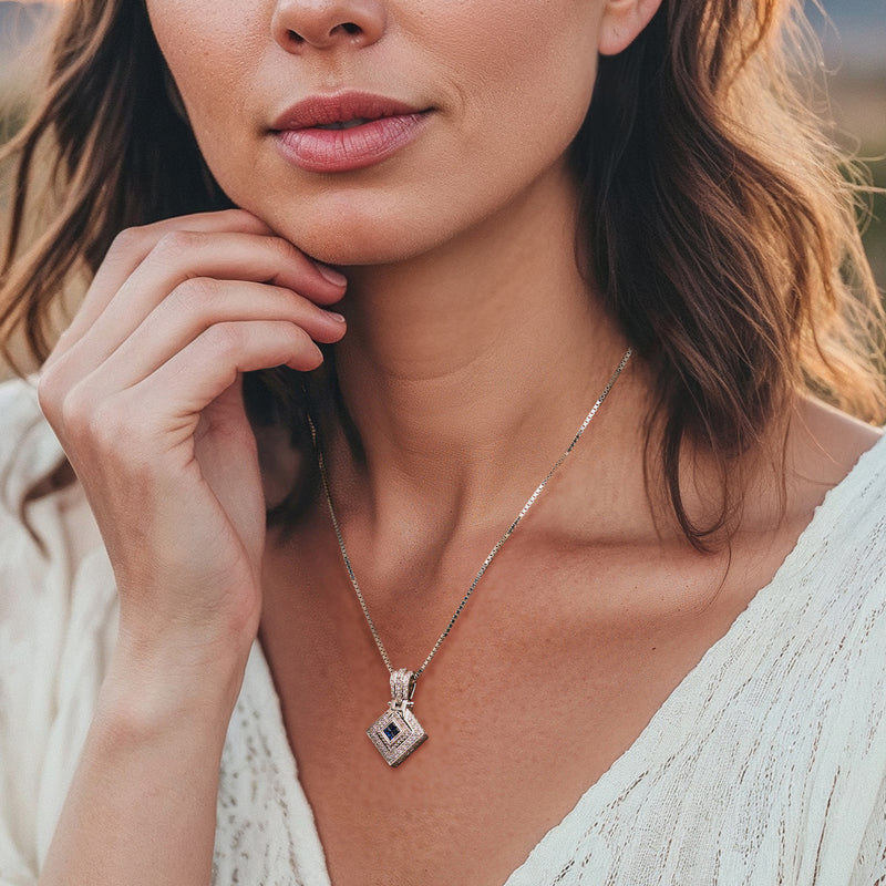 White gold diamond and blue sapphire pendant necklace worn on neckline