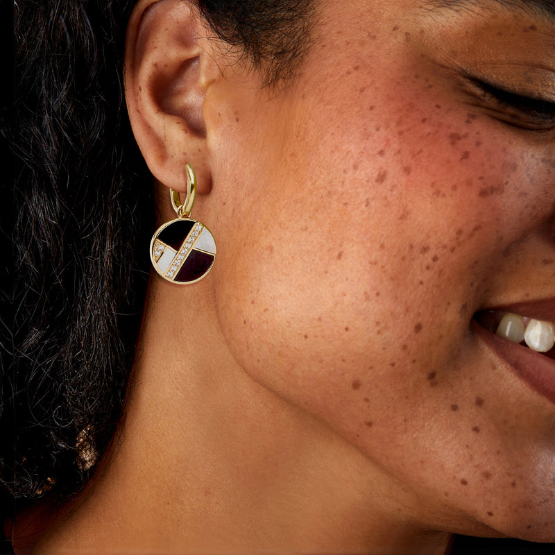 Gold hoop earrings on model with round onyx and mother-of-pearl drop and white crystal border
