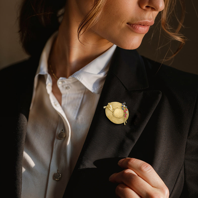 Yellow gold hat pin on blazer lapel with blue sapphire and red ruby accents