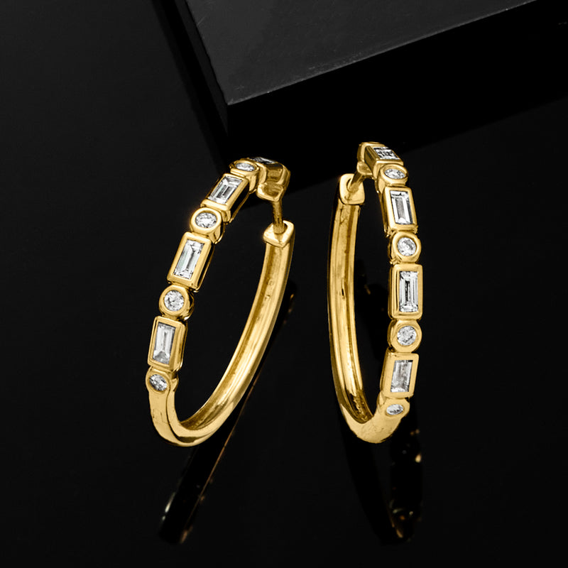 Gold hoop earrings with alternating baguette and round diamond settings, side view