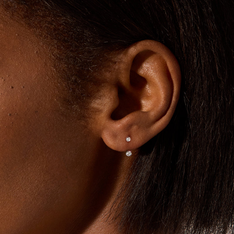 Sterling silver U-hoop earrings with two small bezel-set diamond discs on ear