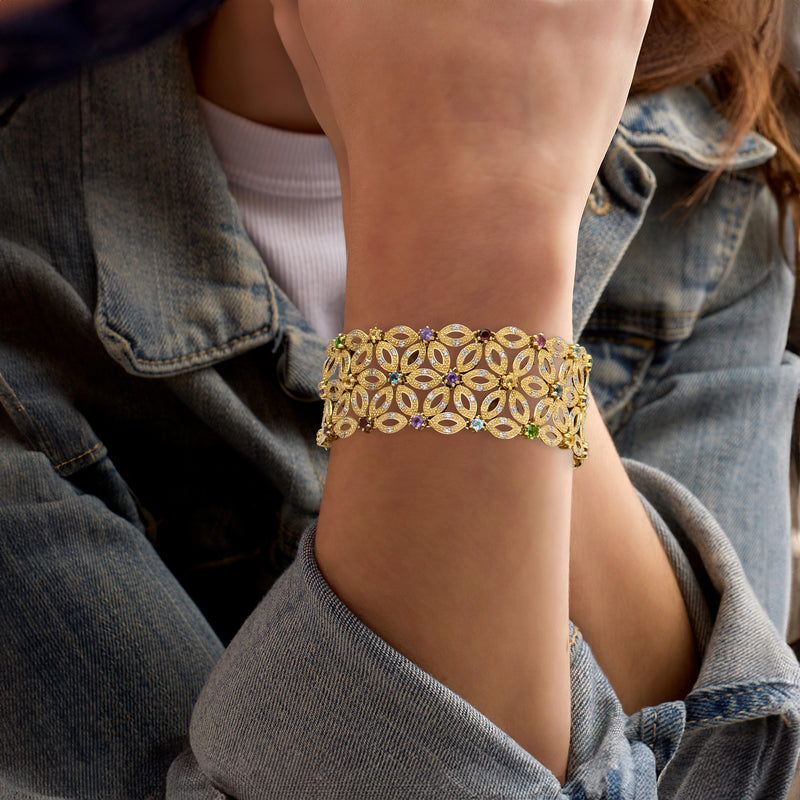 Gold-tone floral gemstone cuff bracelet on wrist with multicolor stones