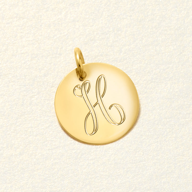 Yellow gold disc charm with engraved HB monogram, shown from a side angle