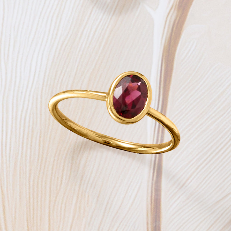 14kt yellow gold ring with oval red garnet bezel, slim band shown at an angle