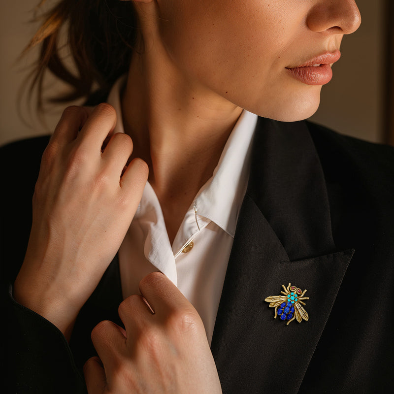 Bumblebee gemstone pin on dark blazer lapel in yellow gold with blue and turquoise stones