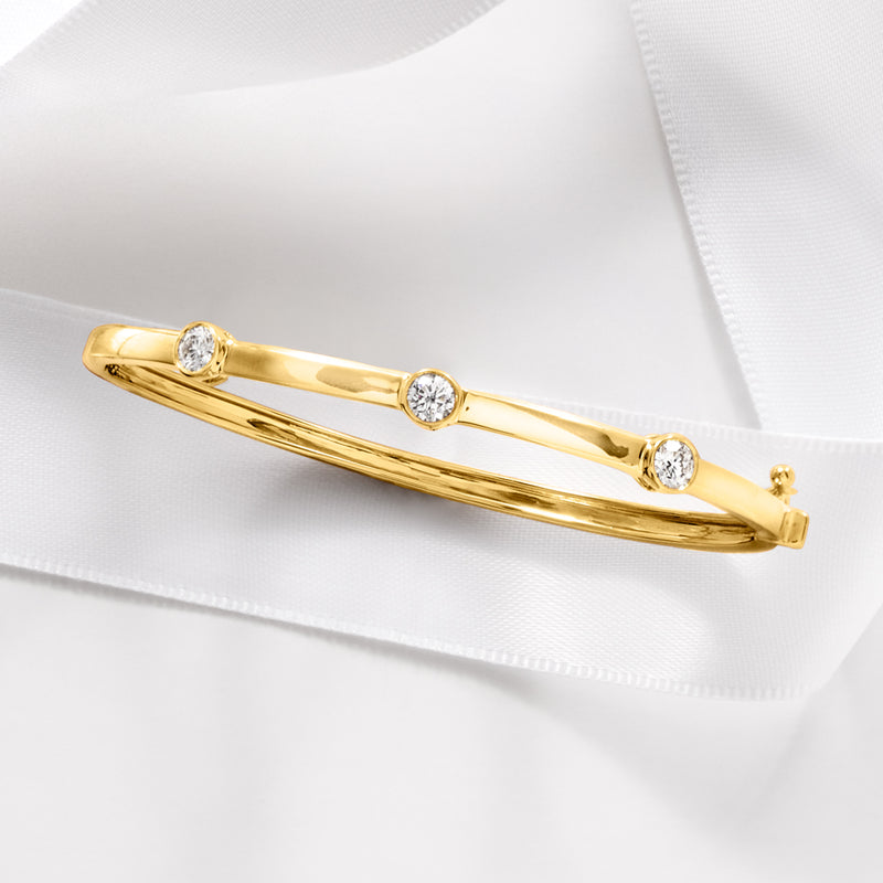 Gold bangle bracelet with round diamond stations and open hinge clasp detail
