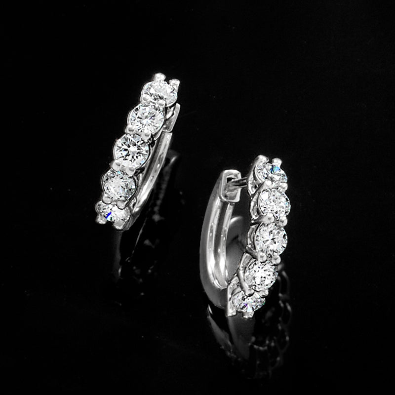 Close-up of platinum five-stone hoop earrings with round diamonds
