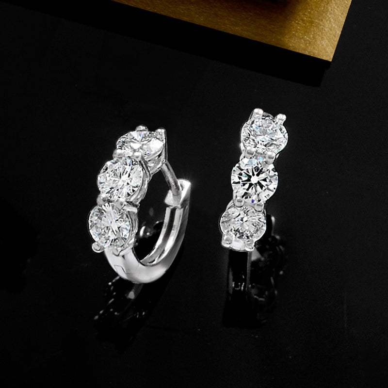 Platinum huggie hoop earrings with three round diamonds, side view