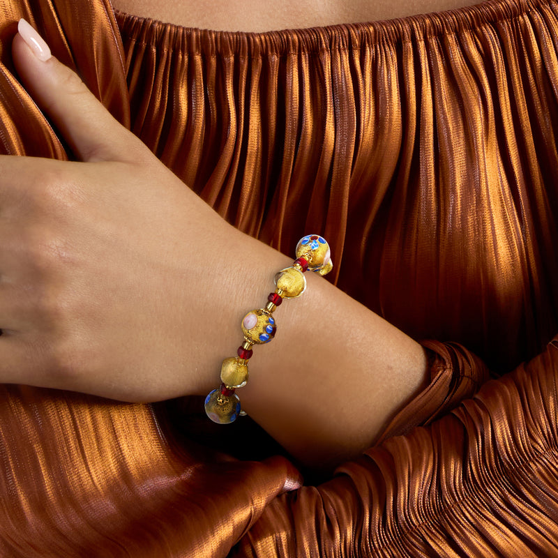Gold-tone Murano glass bead bracelet on wrist with red and blue floral bead accents