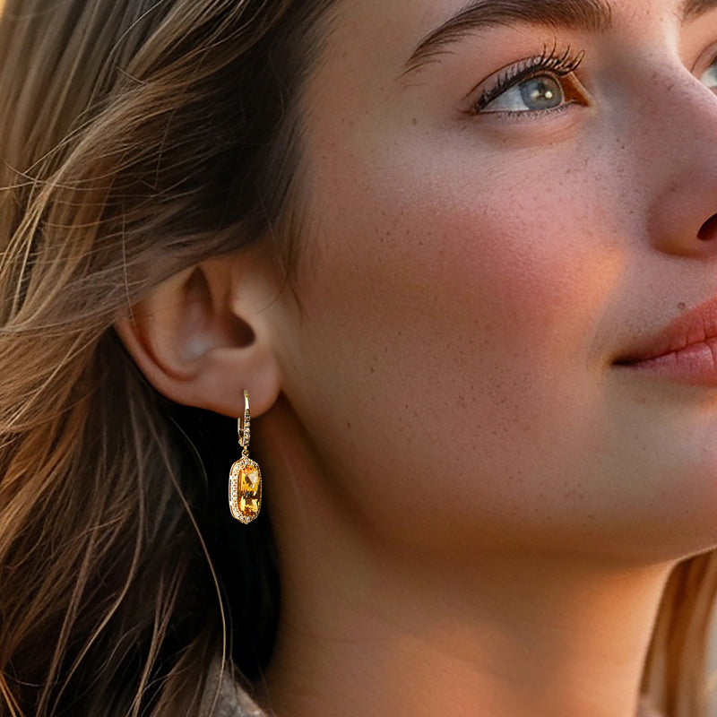 Leverback drop earrings with oval yellow center stone and glittering halo, seen on ear