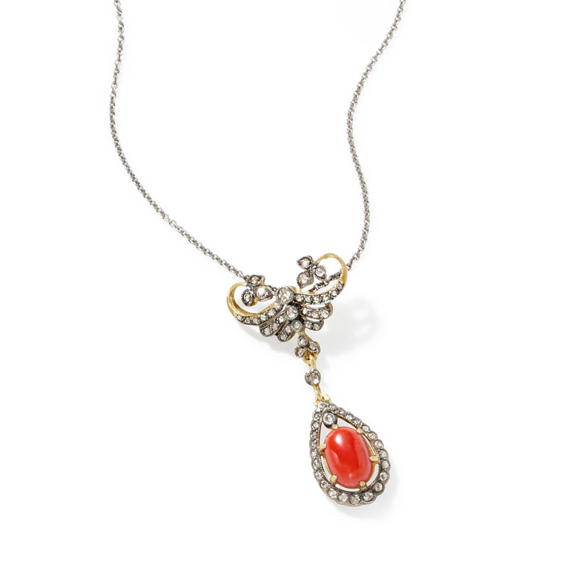 Pendant necklace with red teardrop stone, diamond halo, and gold filigree on silver chain.
