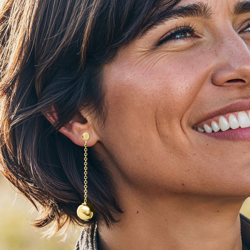 Gold over sterling bead drop earrings with round pendant spheres on linked chain, on wearer