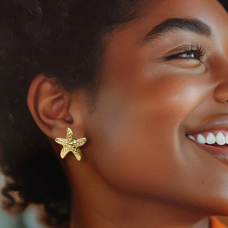 Gold starfish stud earrings on ear, textured star motif