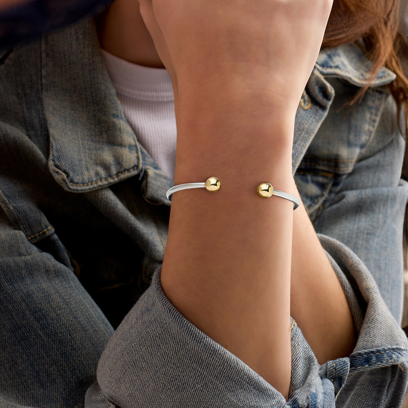Gold-toned bead cuff bracelet on wrist with open silver band