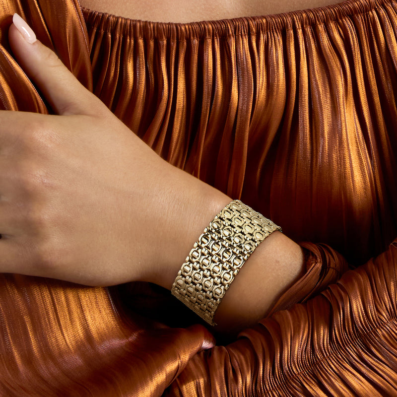 Wide fancy-link 14kt yellow gold bracelet on wrist, mesh-like chain band