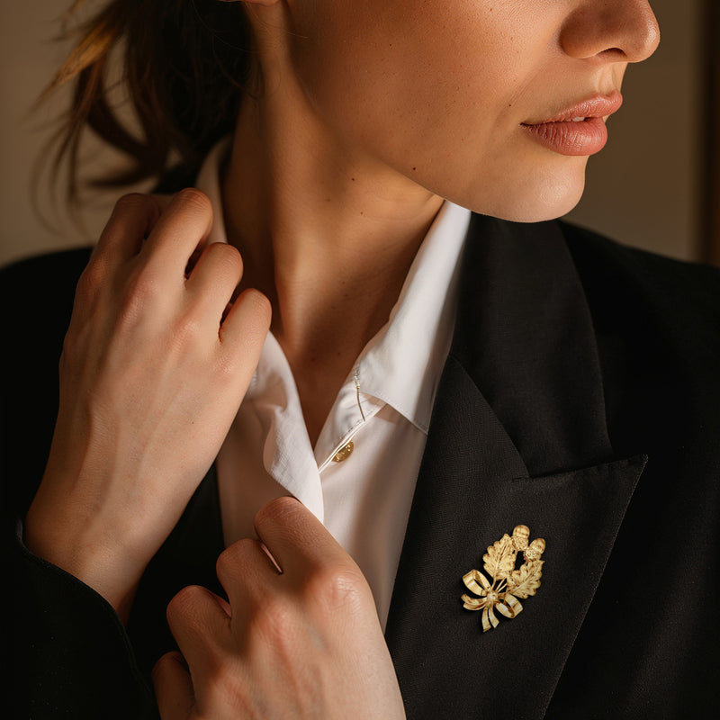 18kt yellow gold acorn and bow pin on dark suit lapel