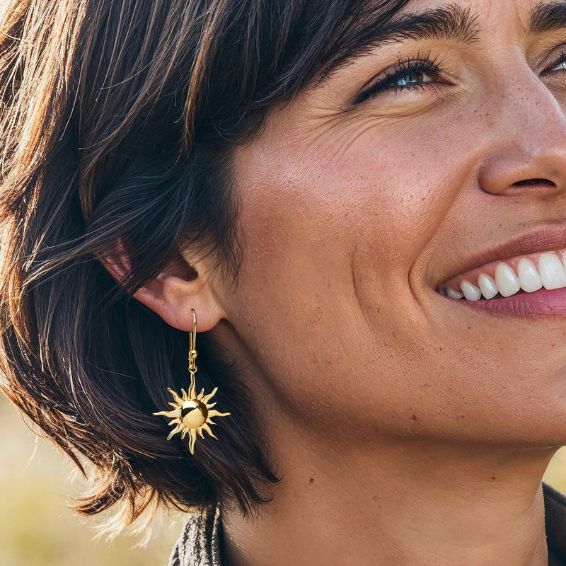 Gold sun dangle earrings on model, textured sun charms on earwire hooks