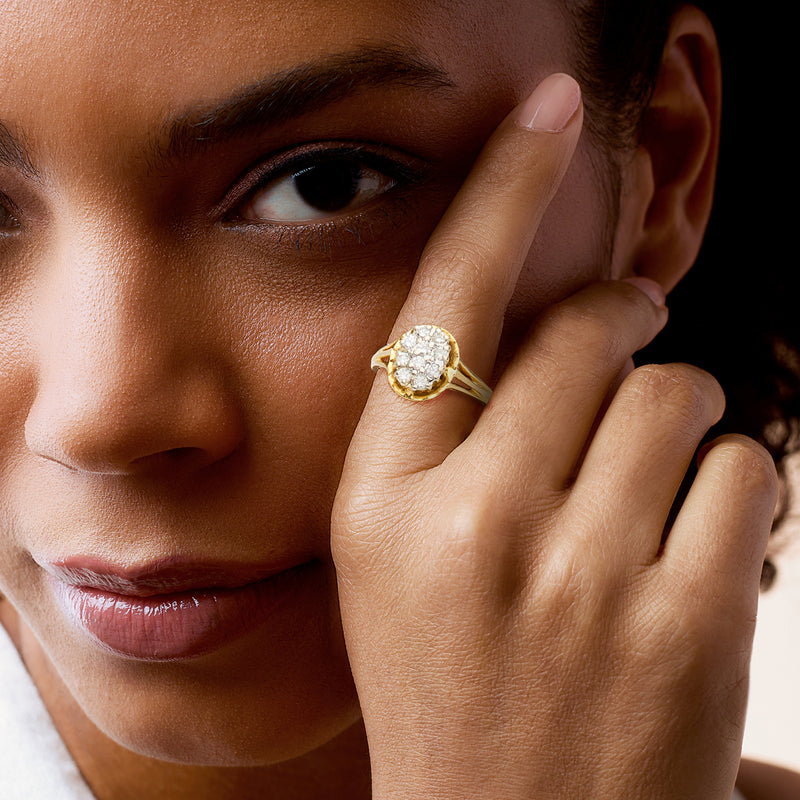 Yellow gold ring with oval diamond cluster, worn on finger