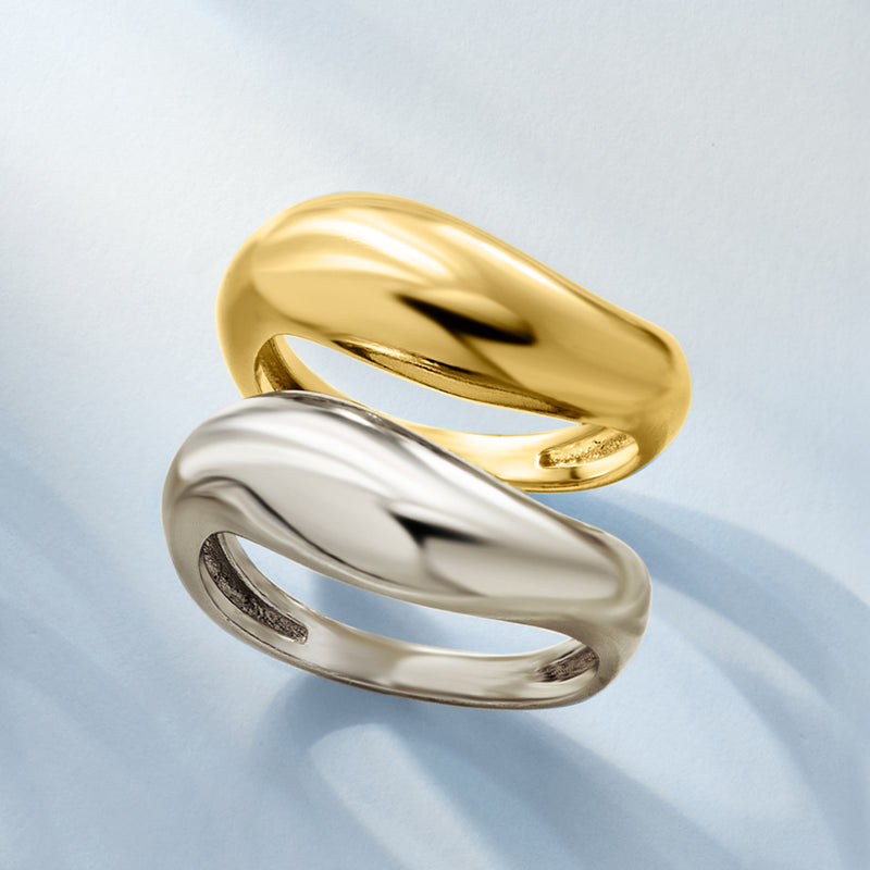 Two-tone sculptural ring set close-up: curved gold and silver bands with shine