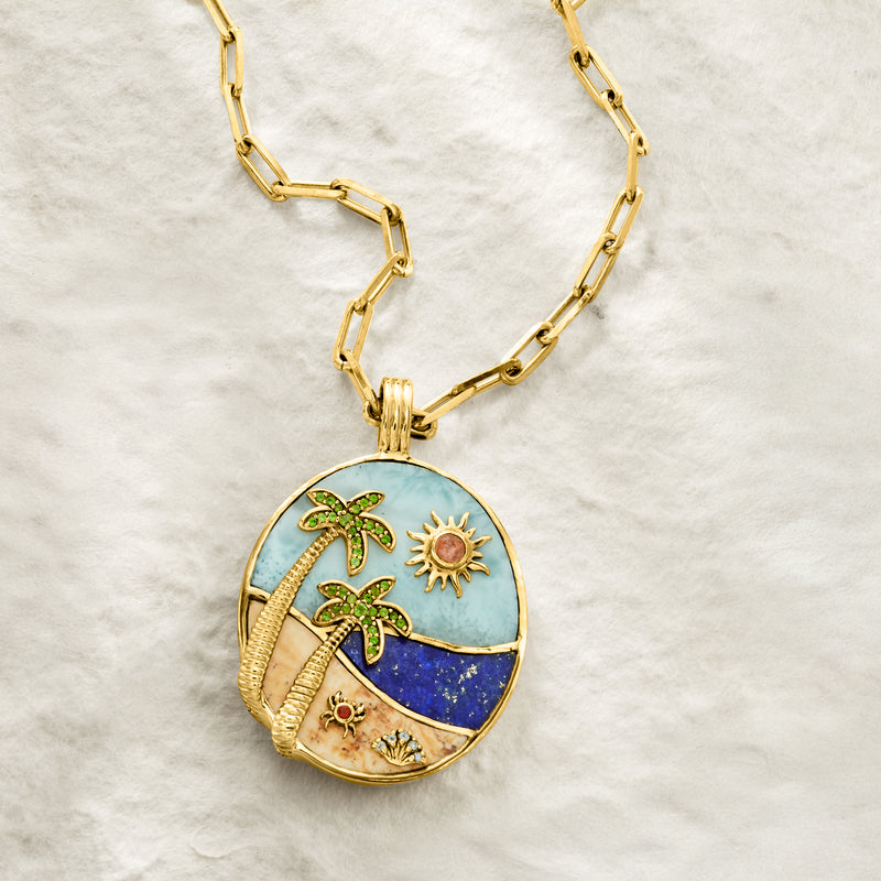 Gold link necklace with oval ocean pendant showing palm trees, sun, and star details
