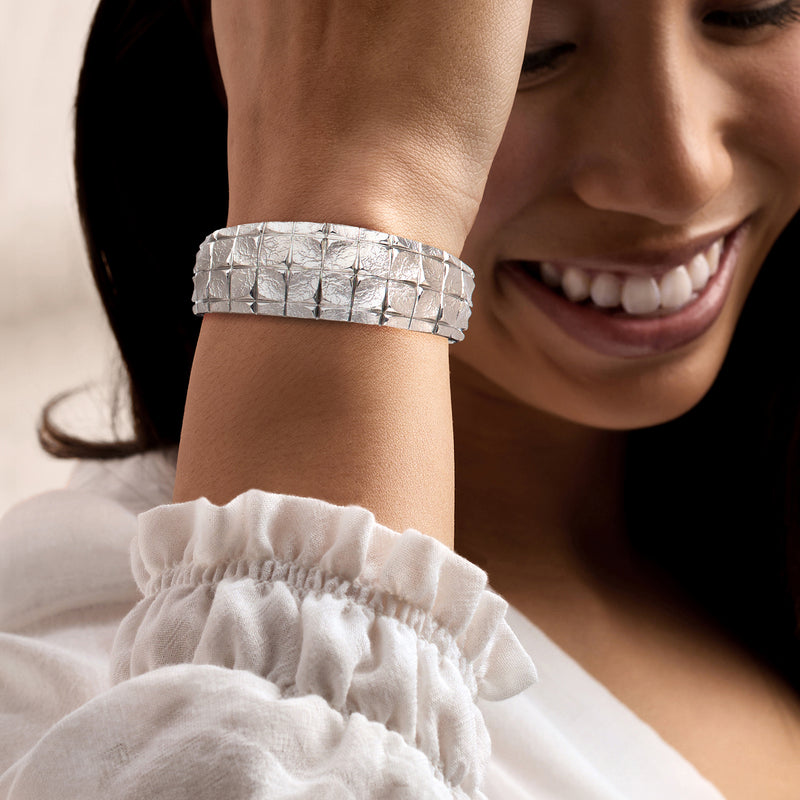 Sterling silver cuff bracelet with square-pattern band, worn on wrist