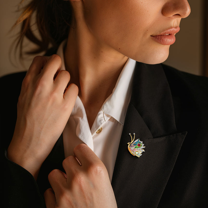 Yellow gold butterfly brooch with multicolor enamel and stone accents on blazer lapel
