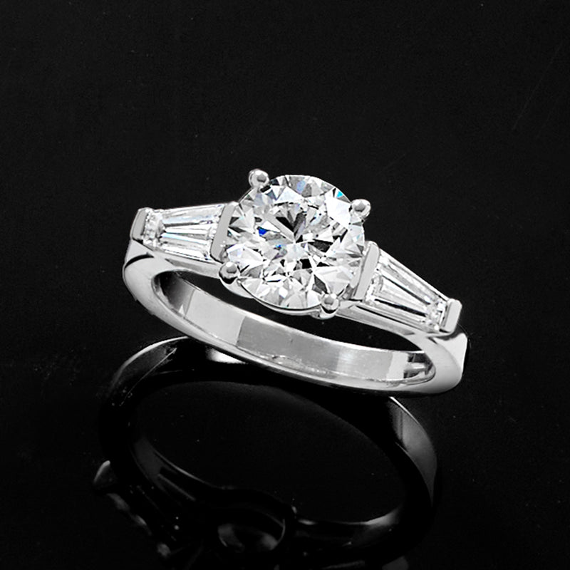 Platinum diamond ring with round center and baguette side stones, angled view