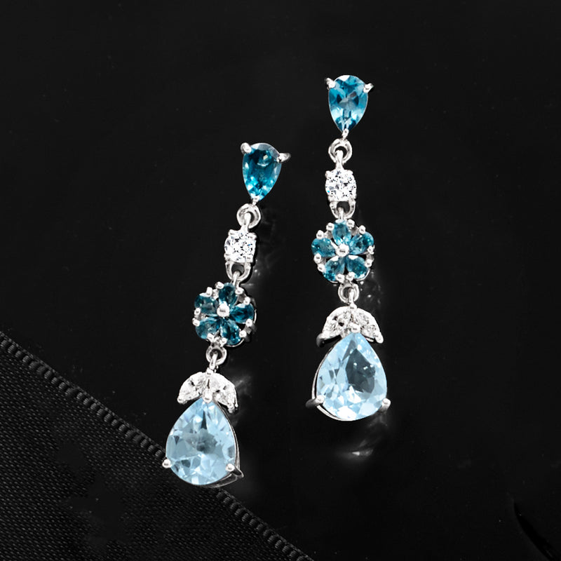 Sterling silver drop earrings with blue topaz floral centers and pear-shaped drops