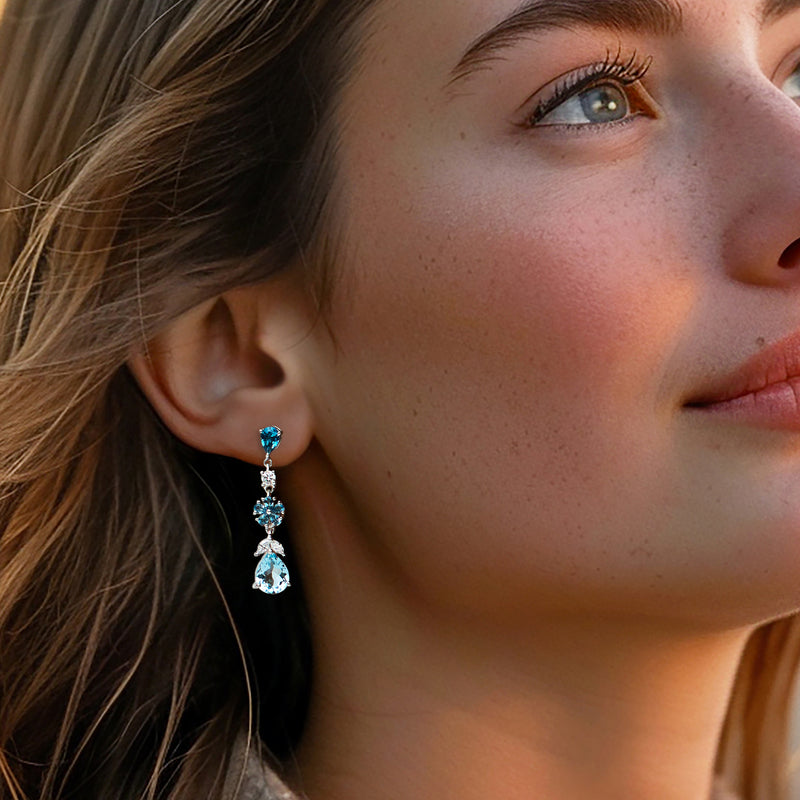 Sterling silver drop earrings with blue topaz and diamond accents on a model
