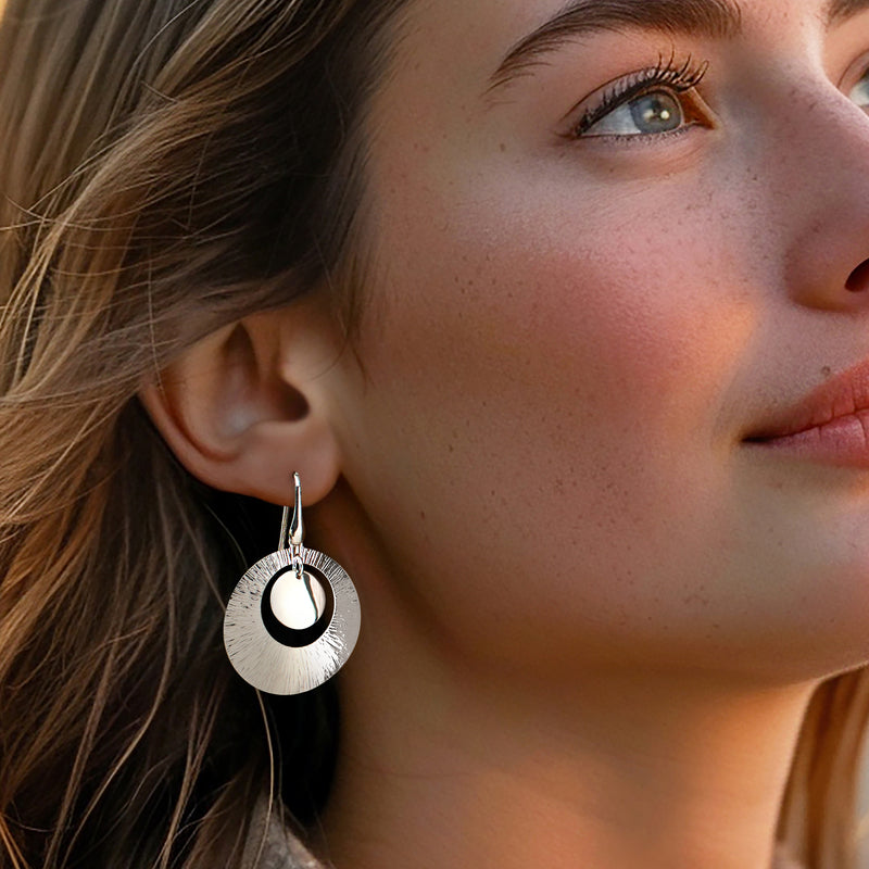 Sterling silver textured disc drop earrings worn on ear with round center and earwire