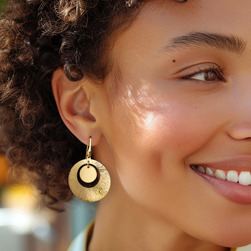 Gold textured circular drop earrings with smooth center ring on earwire, side view.