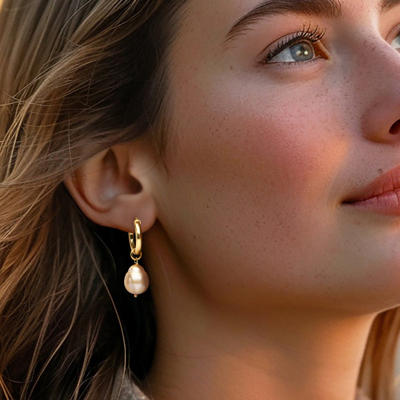 Gold hoop earrings with peach baroque cultured pearl drop dangling on ear
