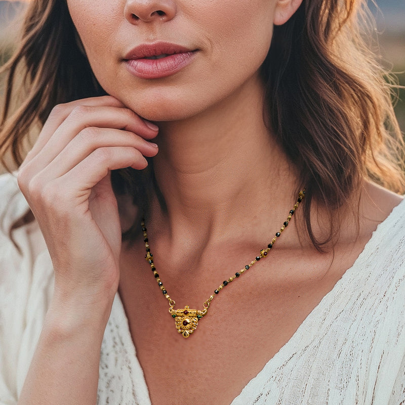 Enamel flower pendant on vintage yellow-gold beaded necklace with dark and gold beads