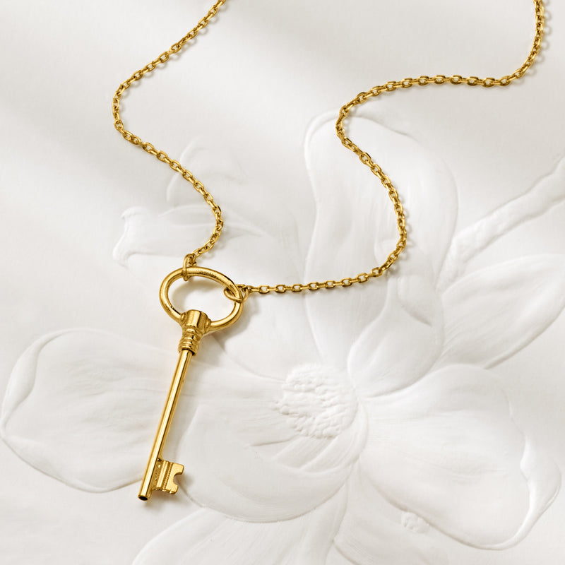 Yellow gold key pendant necklace close-up with round ring and long key shape