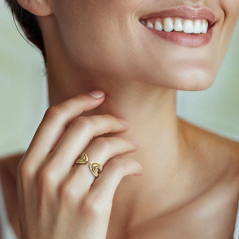 Yellow gold open-space cuff ring with swirl motifs on a finger