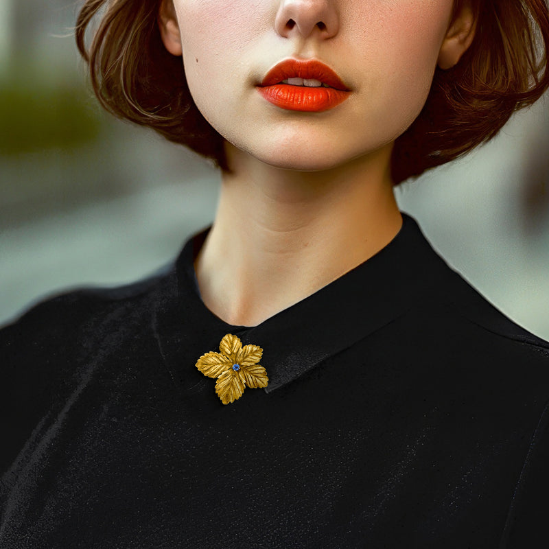 Gold flower lapel pin with blue center on black top