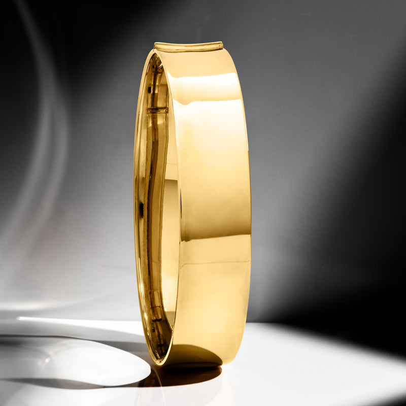 Yellow gold bangle bracelet, side view of glossy smooth oval cuff