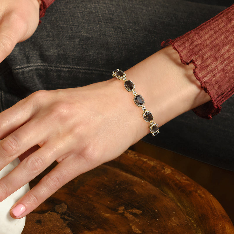 Gold gemstone bracelet with dark oval smoky quartz stones and diamond accents on wrist