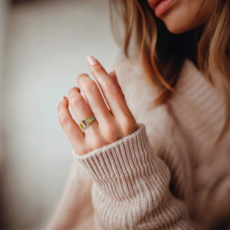 Gold multi-gemstone ring on hand, rectangular purple, green, and light blue stones