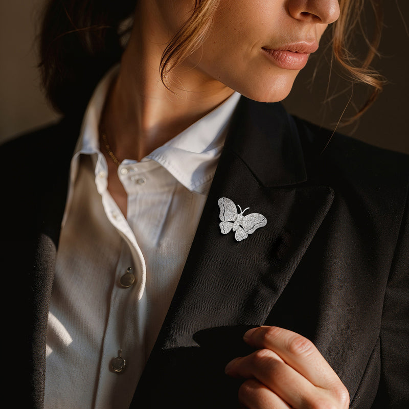 Diamond butterfly lapel pin in 18kt white gold, secured on a dark blazer