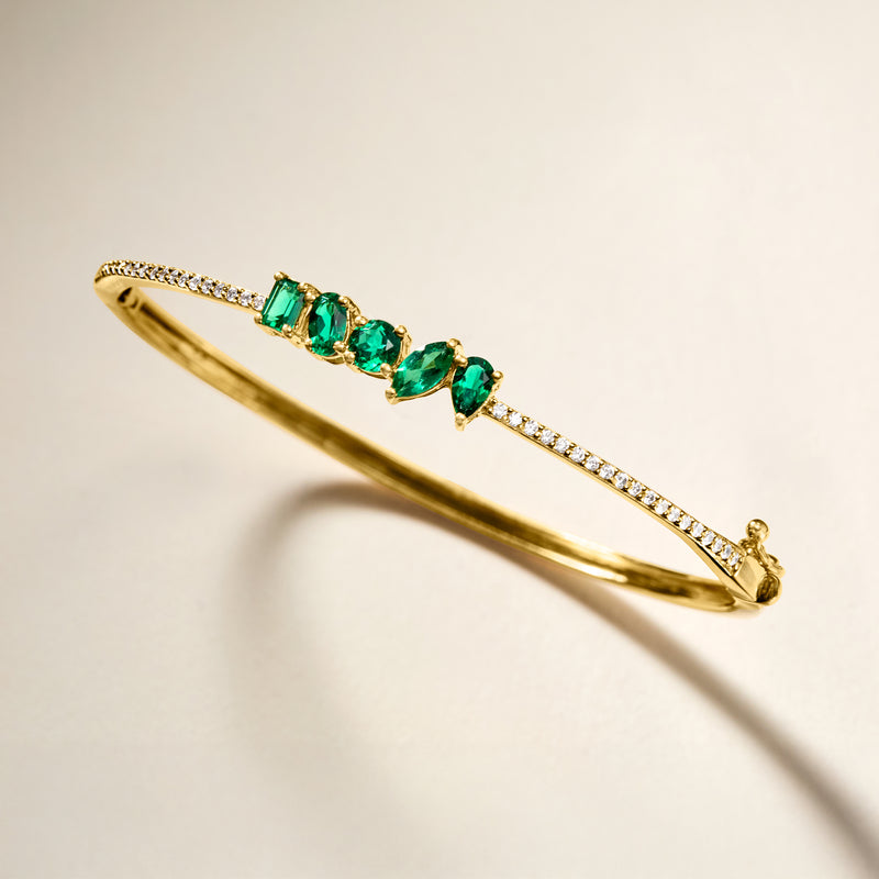 Gold bangle bracelet with lab-grown emeralds and diamond accents