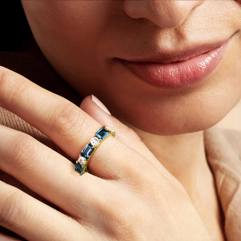 Gold ring on hand with baguette blue topaz and round diamond accents