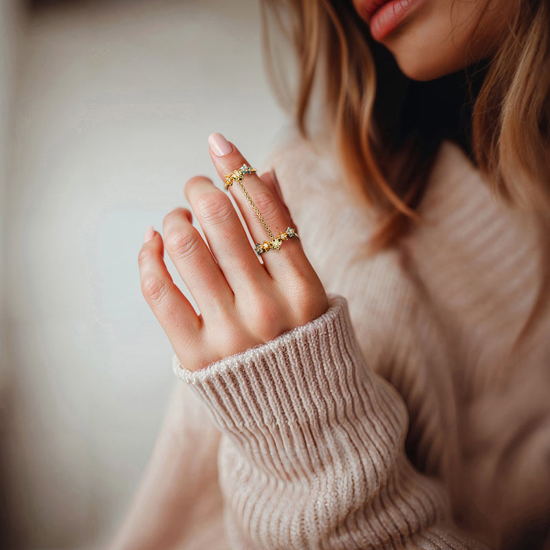 Gold-tone flower gemstone double ring on hand, blue and yellow stone clusters