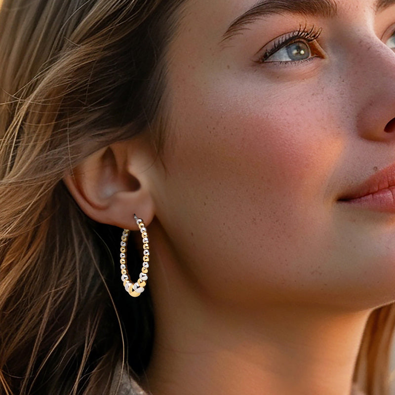 Model wearing two-tone bead hoop earrings with small graduated silver and gold beads